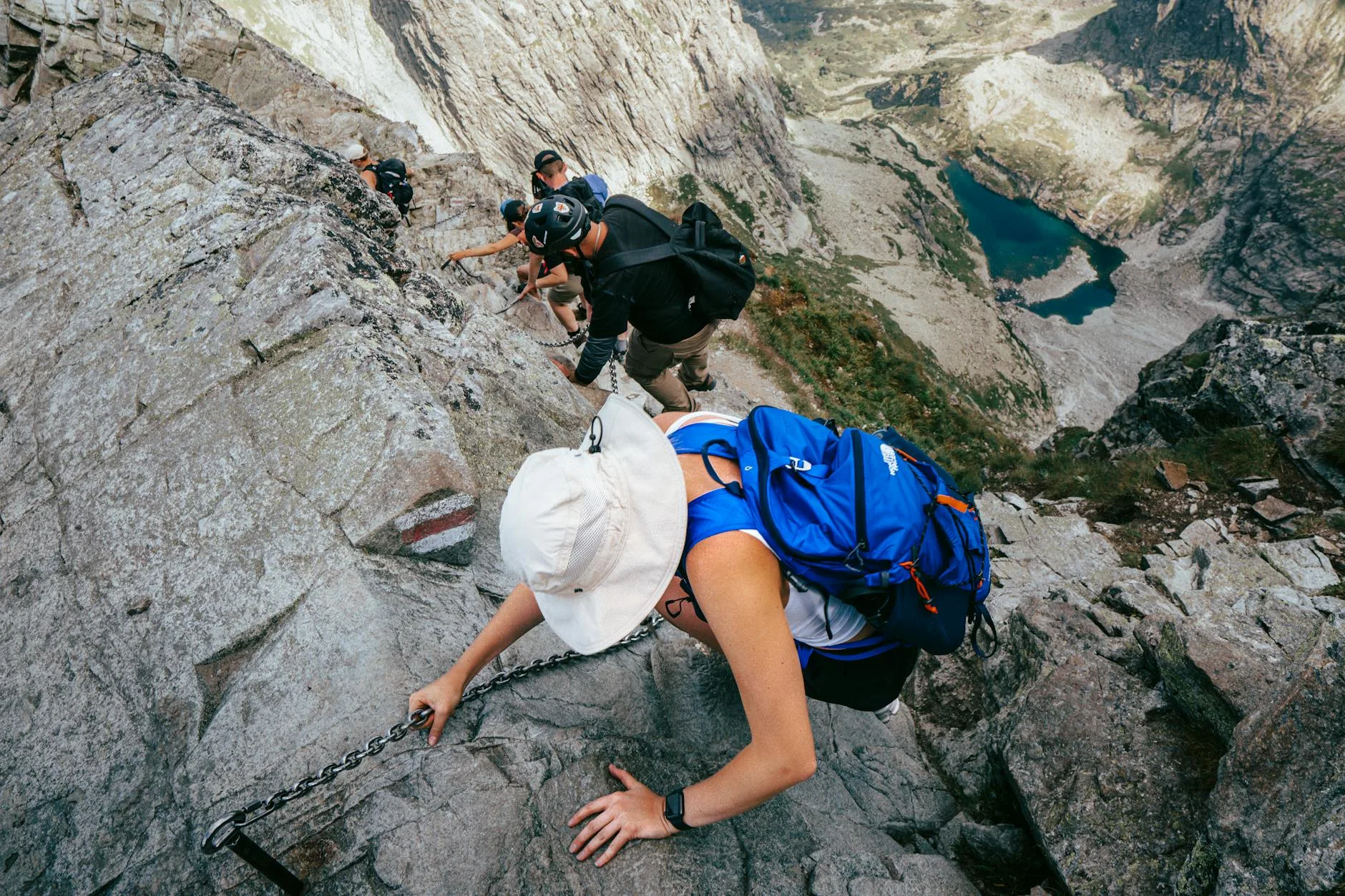 Szlak wśród skał nad górskim jeziorem otoczonym szczytami