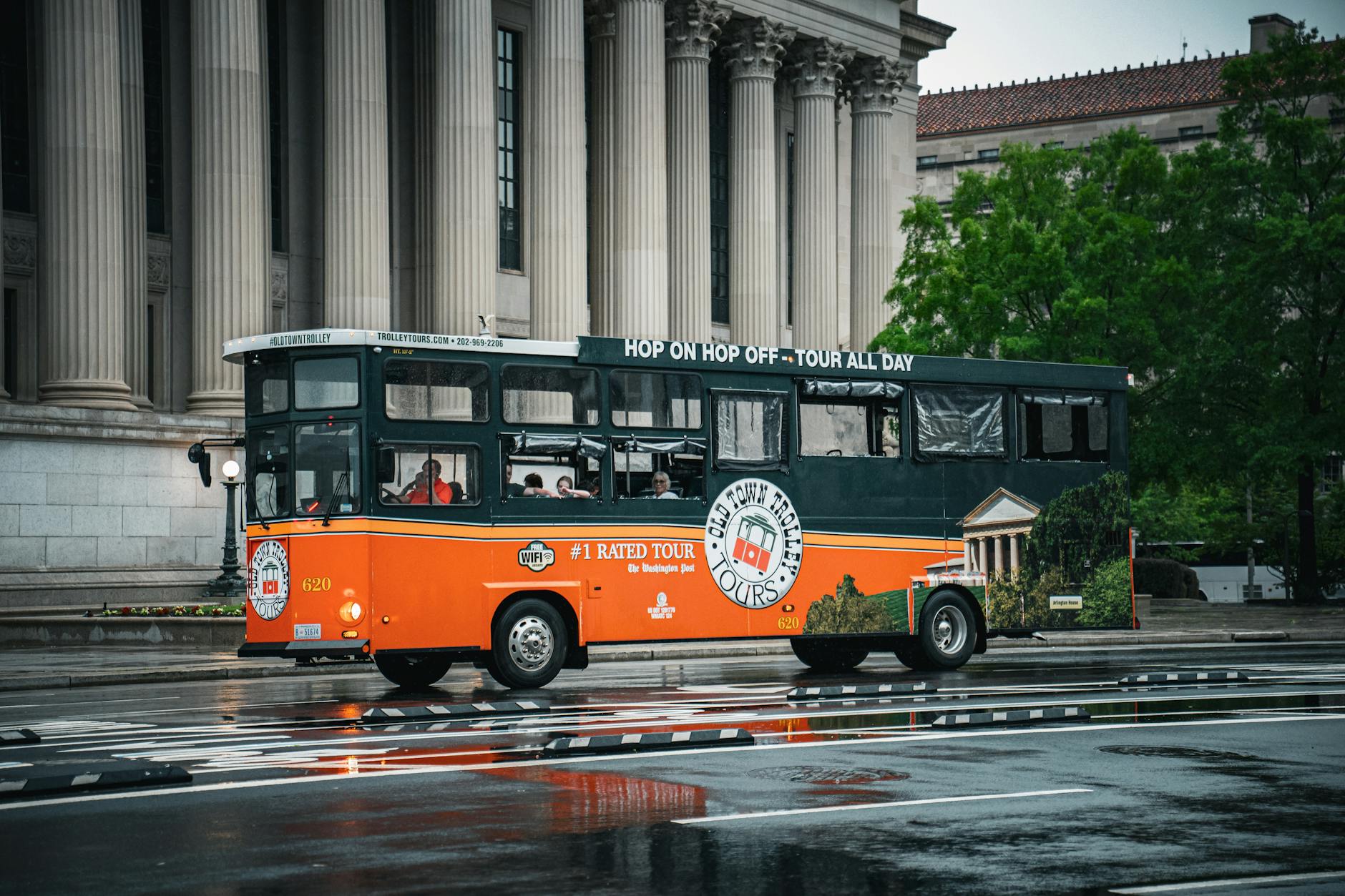 Piętrowy autobus turystyczny na mokrej ulicy przy zabytkowych budynkach