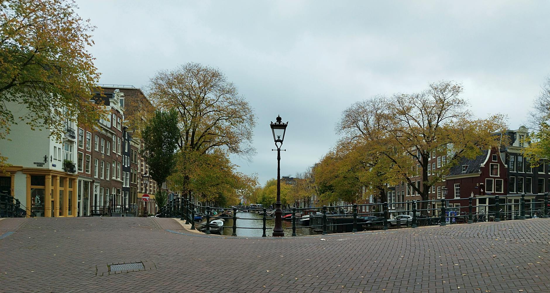 Jesienny kanał w Amsterdamie otoczony drzewami i kamienicami