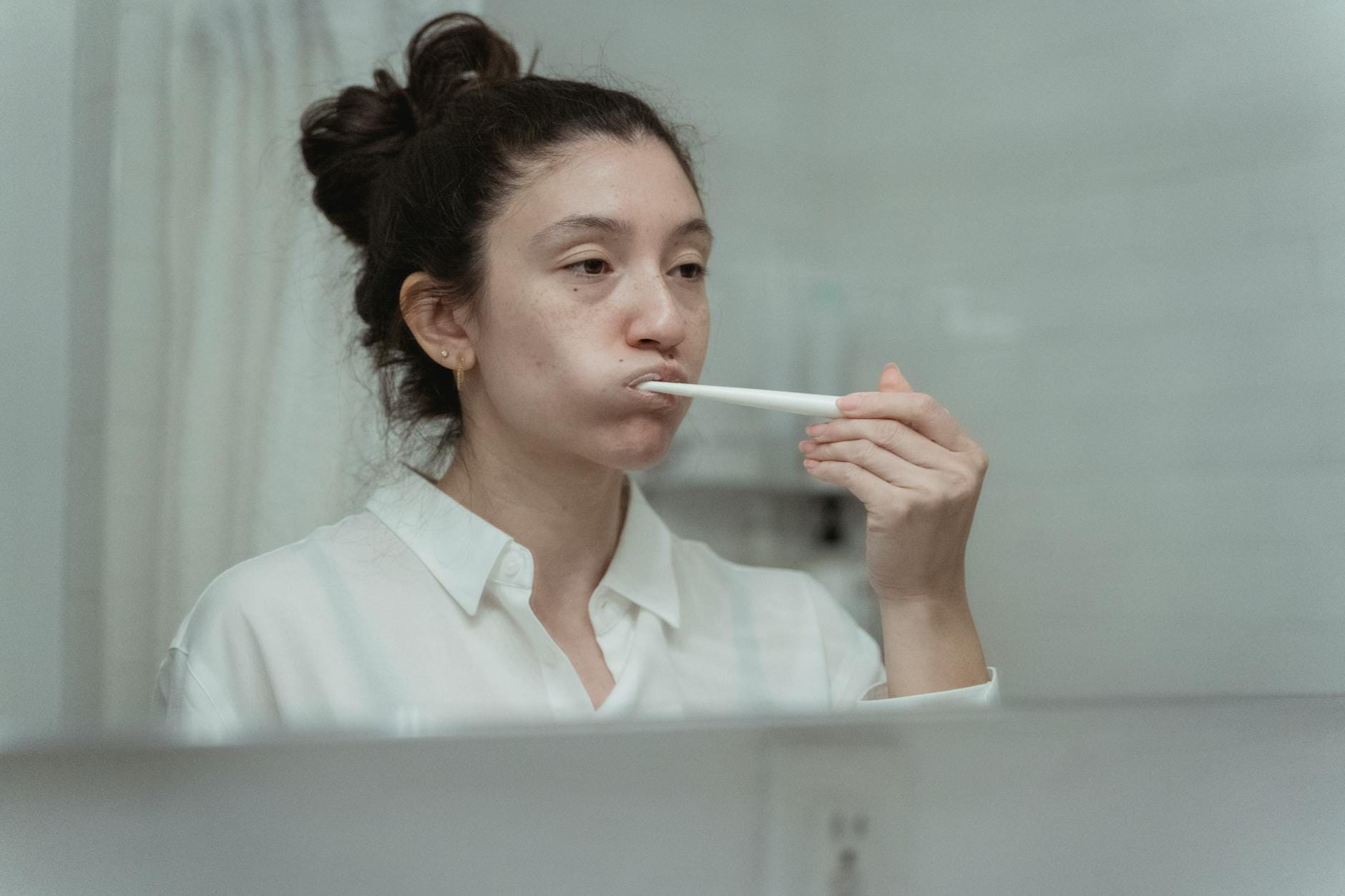 Kobieta w łazience myje zęby szczoteczką dbając o higienę jamy ustnej