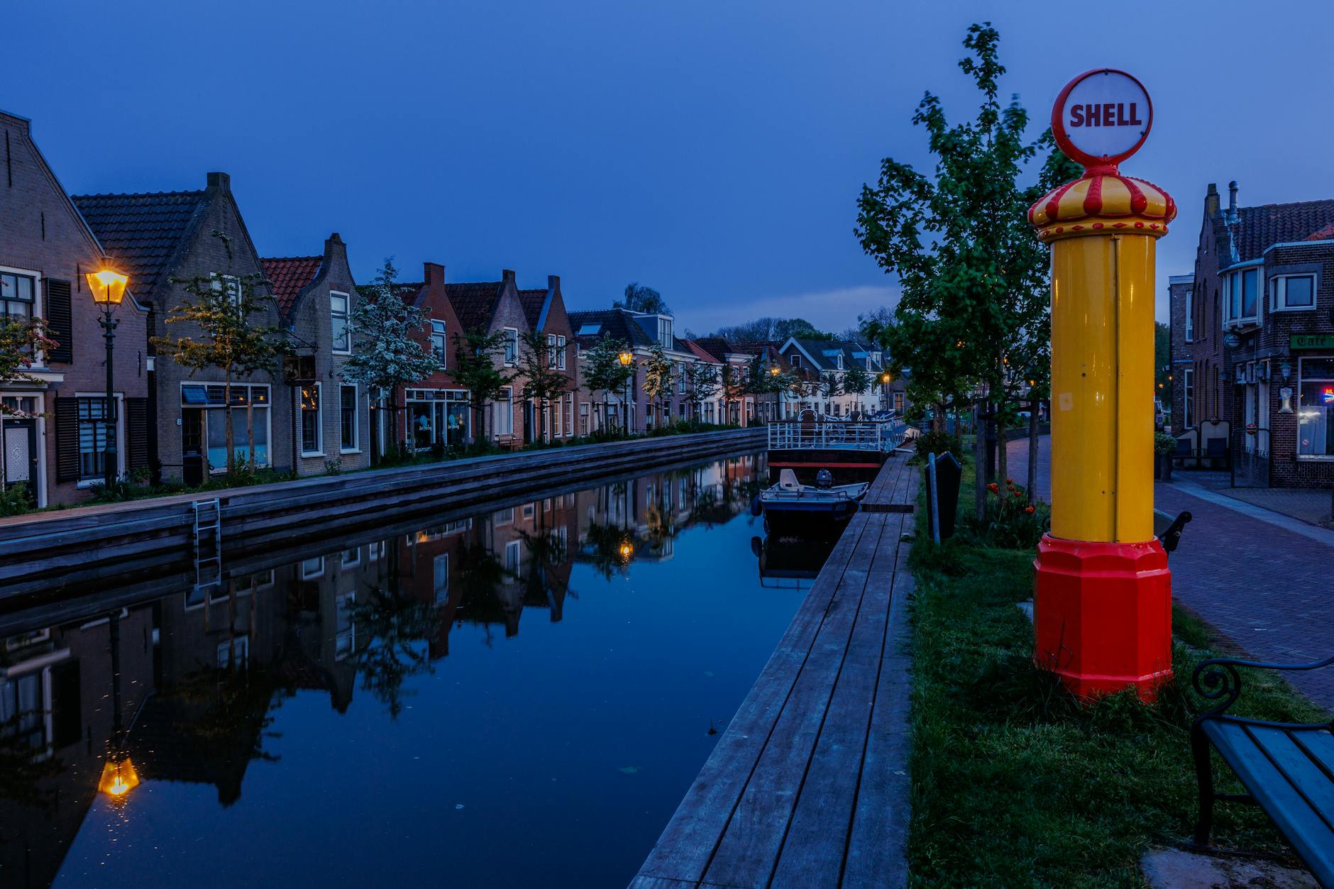 Wieczorny kanał w Schipluiden z tradycyjnymi domami i szyldem Shell Wieczorny kanał w Schipluiden z tradycyjnymi domami i szyldem Shell